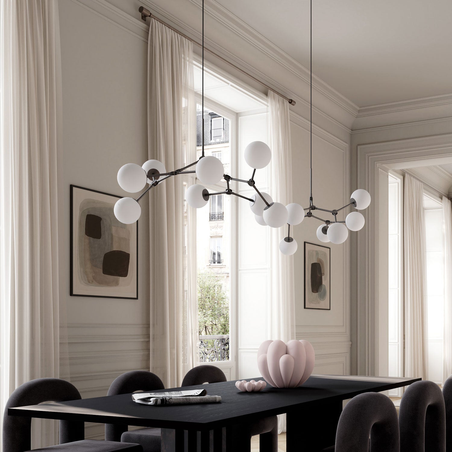 Modern multi-arm Drop chandelier bulp with white spherical glass globes suspended over a dark dining table in a bright, elegant room with cream curtains and framed abstract wall art.